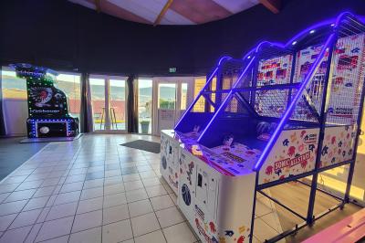 Salle de réception avec une longue table dressée, des chaises rouges et noires, et une fresque murale représentant un…