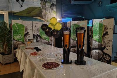 Salle de réception avec une longue table dressée, des chaises rouges et noires, et une fresque murale représentant un…