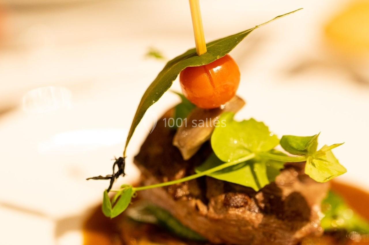 Plat gastronomique composé de viande, légumes et sauce, présenté avec une décoration soignée sur une assiette blanche.