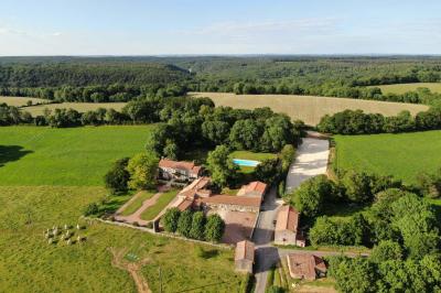 Vue sur un jardin avec pelouse, allées en gravier, parterre de fleurs rouges et bâtiments en pierre sous un ciel dégagé.