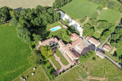 Vue sur un jardin avec pelouse, allées en gravier, parterre de fleurs rouges et bâtiments en pierre sous un ciel dégagé.