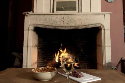 Vue sur un jardin avec pelouse, allées en gravier, parterre de fleurs rouges et bâtiments en pierre sous un ciel dégagé.