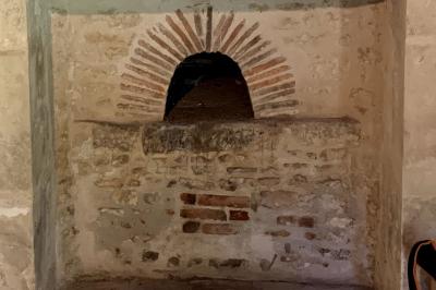 Vue sur un jardin avec pelouse, allées en gravier, parterre de fleurs rouges et bâtiments en pierre sous un ciel dégagé.