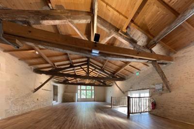 Vue sur un jardin avec pelouse, allées en gravier, parterre de fleurs rouges et bâtiments en pierre sous un ciel dégagé.