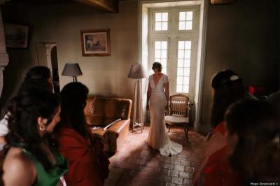 Vue sur un jardin avec pelouse, allées en gravier, parterre de fleurs rouges et bâtiments en pierre sous un ciel dégagé.