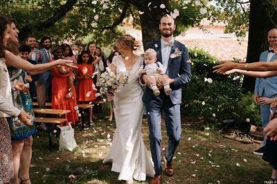 Vue sur un jardin avec pelouse, allées en gravier, parterre de fleurs rouges et bâtiments en pierre sous un ciel dégagé.