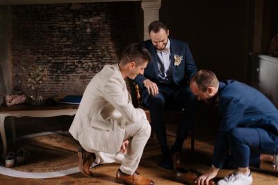Vue sur un jardin avec pelouse, allées en gravier, parterre de fleurs rouges et bâtiments en pierre sous un ciel dégagé.