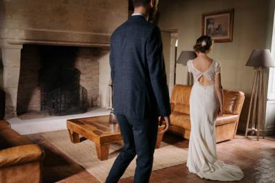 Vue sur un jardin avec pelouse, allées en gravier, parterre de fleurs rouges et bâtiments en pierre sous un ciel dégagé.