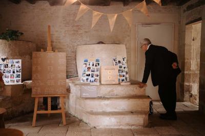 Vue sur un jardin avec pelouse, allées en gravier, parterre de fleurs rouges et bâtiments en pierre sous un ciel dégagé.