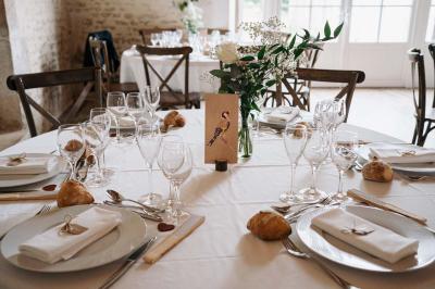 Vue sur un jardin avec pelouse, allées en gravier, parterre de fleurs rouges et bâtiments en pierre sous un ciel dégagé.