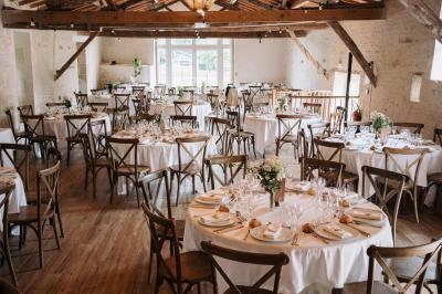 Vue sur un jardin avec pelouse, allées en gravier, parterre de fleurs rouges et bâtiments en pierre sous un ciel dégagé.