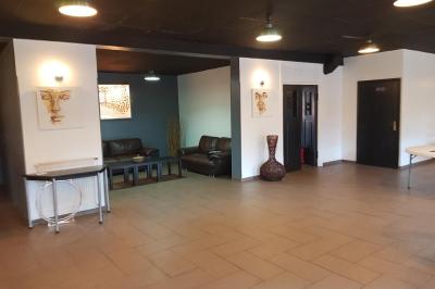 Salle de réception décorée avec des tables rondes dressées, nappes blanches et éclairage suspendu.