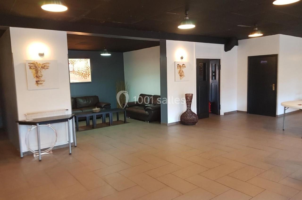 Salle spacieuse avec carrelage au sol, canapés en cuir, décorations murales et éclairage suspendu.