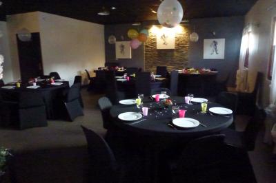 Salle de réception décorée avec des tables rondes dressées, nappes blanches et éclairage suspendu.