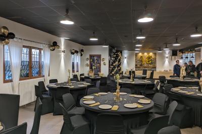 Salle de réception décorée avec des tables rondes dressées, nappes blanches et éclairage suspendu.