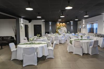 Salle de réception décorée avec des tables rondes dressées, nappes blanches et éclairage suspendu.