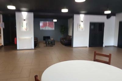 Salle de réception décorée avec des tables rondes dressées, nappes blanches et éclairage suspendu.