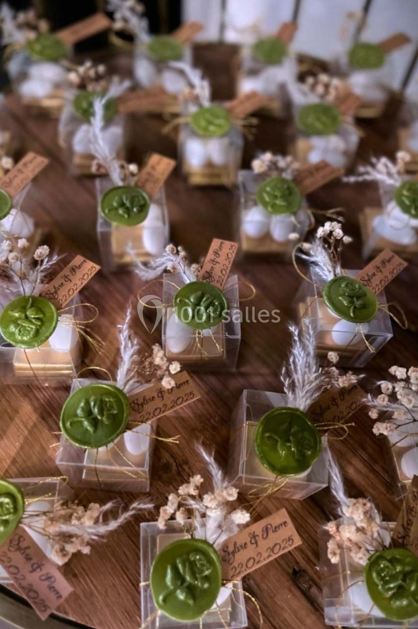 Petits coffrets transparents contenant des dragées, décorés de cachets de cire verte et de fleurs séchées.