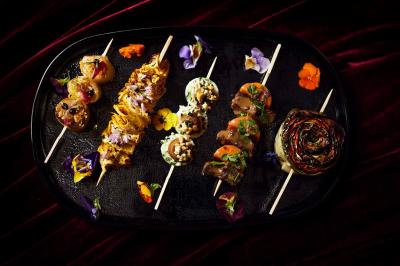 Brochette de viande et légumes garnie de persil et de sauce, servie sur une assiette décorative.