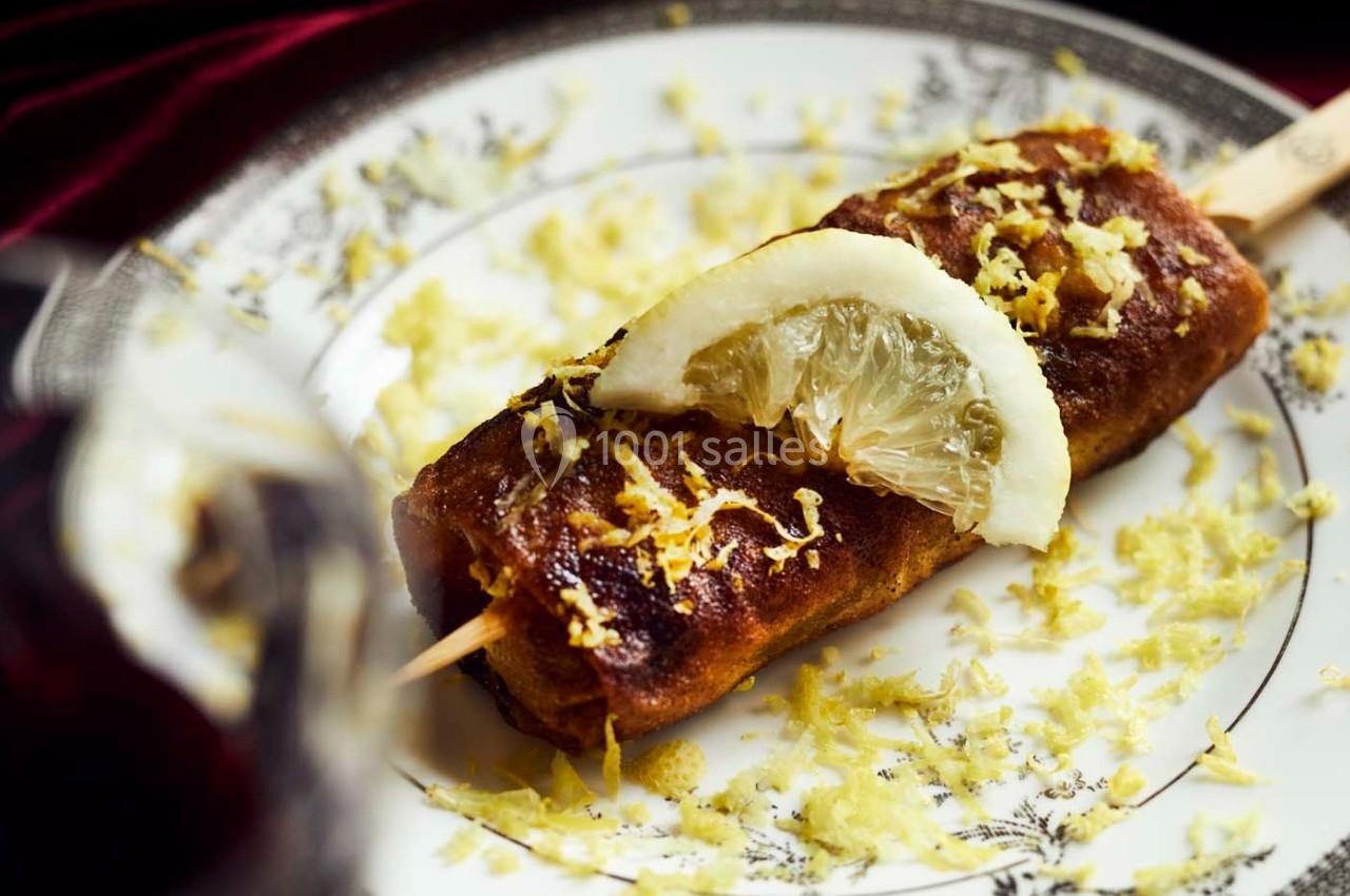 Brochette sucrée garnie de zeste et d'une tranche de citron, servie sur une assiette décorative.