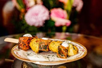 Brochette de viande et légumes garnie de persil et de sauce, servie sur une assiette décorative.
