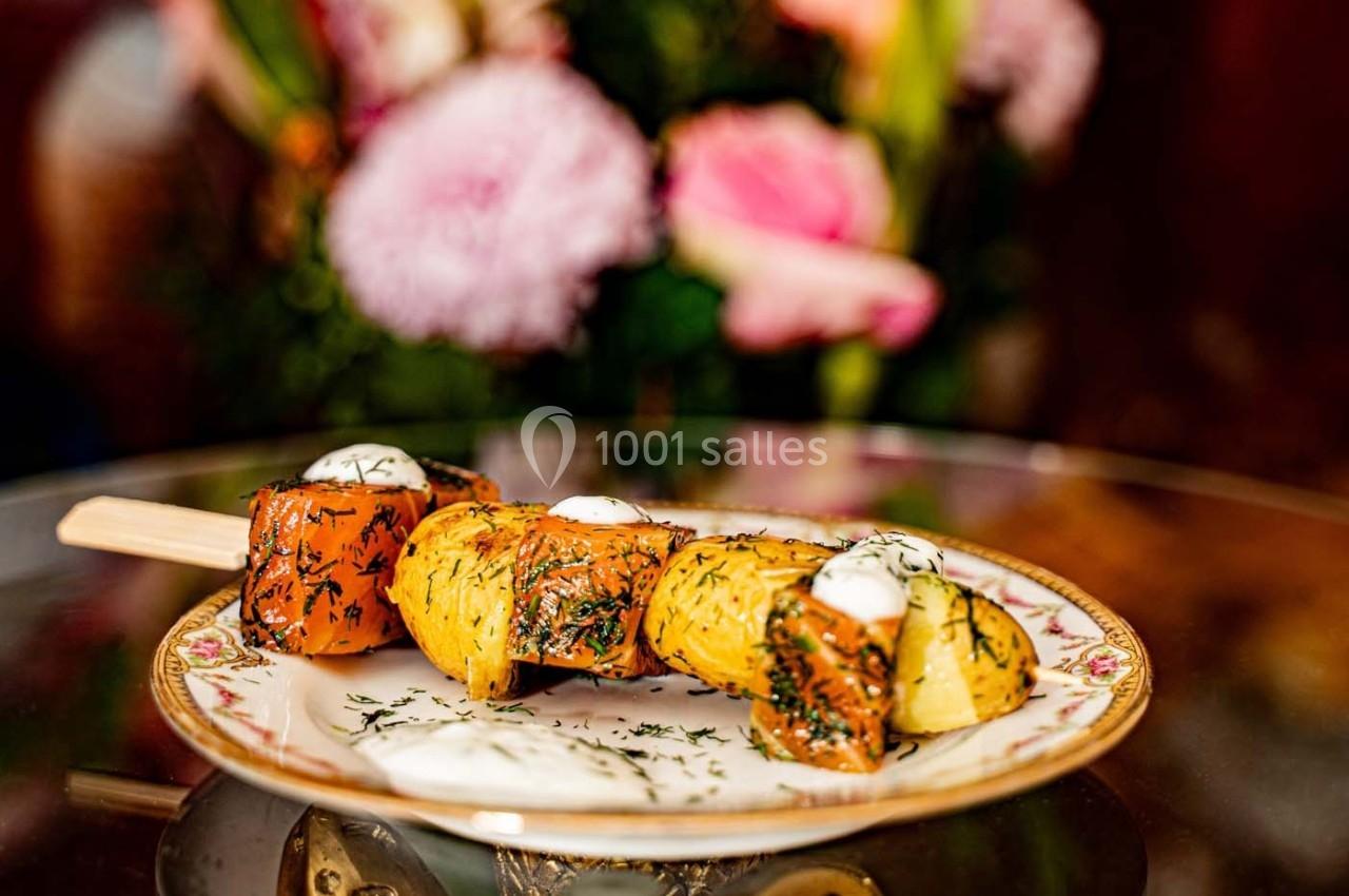 Brochette de légumes grillés garnie d'herbes et de crème, servie sur une assiette en porcelaine avec un fond floral.