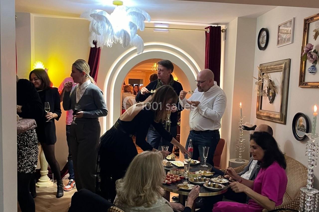 Personnes partageant un apéritif dans un salon décoré avec des arches lumineuses et des chandeliers.
