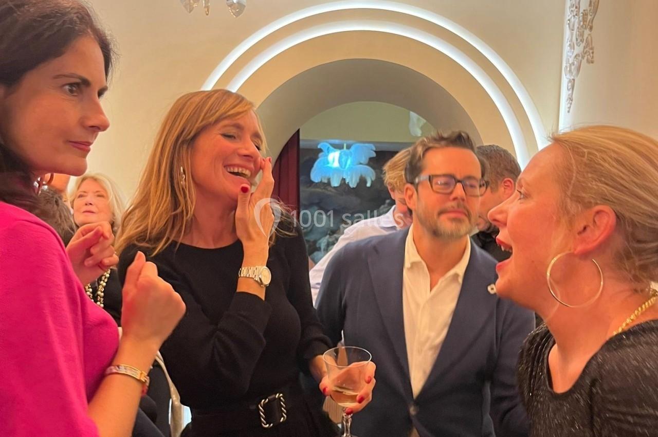 Des personnes discutent et rient lors d'un événement social dans un intérieur éclairé.