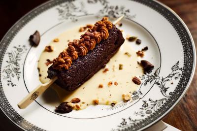 Assiette de desserts raffinés avec mousse, éclats de maïs soufflé et crème, présentée sur une nappe rouge.