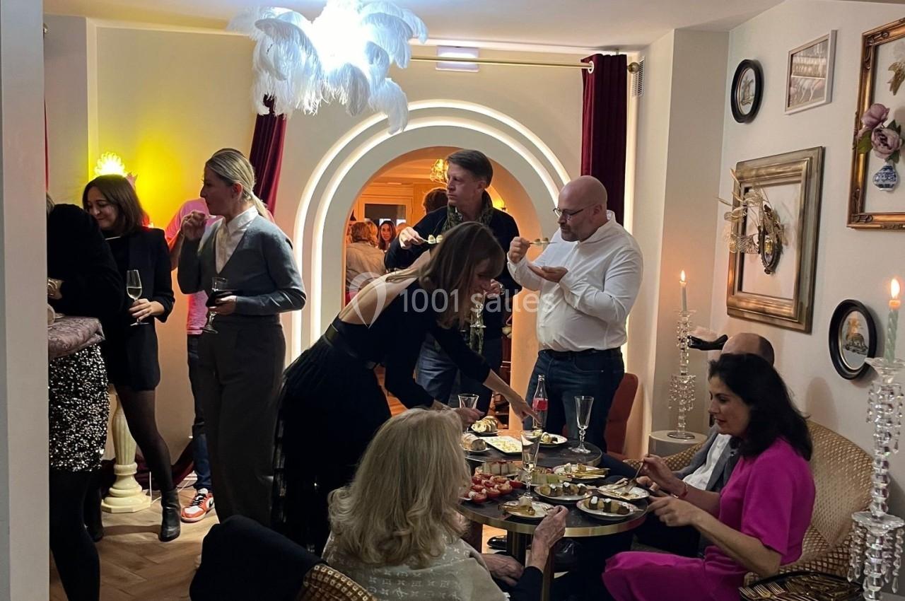 Personnes réunies dans un salon élégant, partageant un buffet et discutant dans une ambiance conviviale.