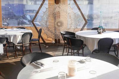 Plantes en pot sur une terrasse couverte avec des tables dressées et des chaises en osier.