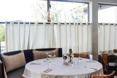 Plantes en pot sur une terrasse couverte avec des tables dressées et des chaises en osier.