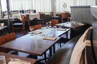 Plantes en pot sur une terrasse couverte avec des tables dressées et des chaises en osier.