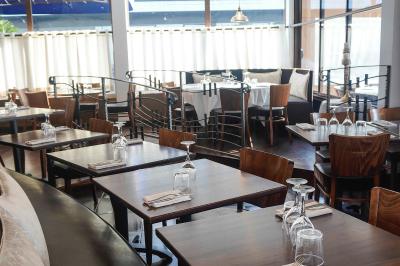 Plantes en pot sur une terrasse couverte avec des tables dressées et des chaises en osier.