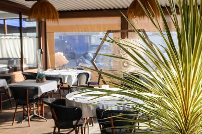 Plantes en pot sur une terrasse couverte avec des tables dressées et des chaises en osier.