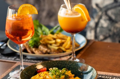 Desserts variés sur une table, incluant un tiramisu décoré d'une tranche d'orange, une mousse au chocolat et un cappuccino.