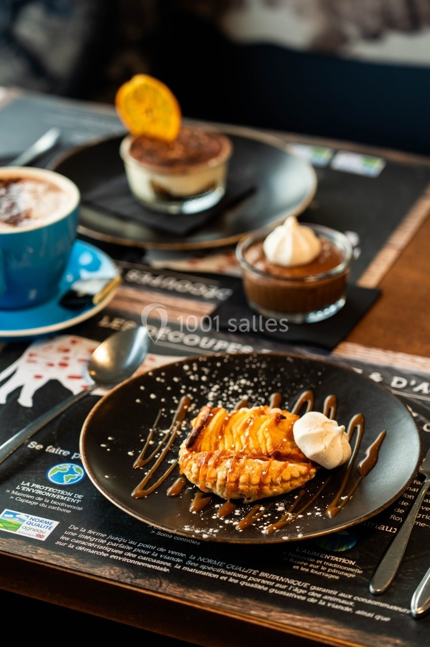 Assiette de dessert avec tarte aux pommes, crème fouettée et caramel, accompagnée de boissons et autres desserts.