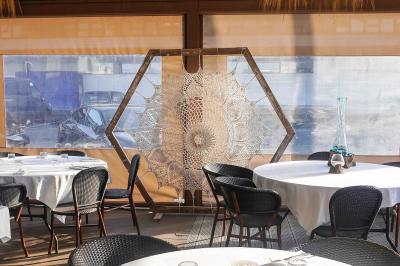 Plantes vertes en pot décorant une terrasse couverte avec des tables et des chaises disposées en arrière-plan.