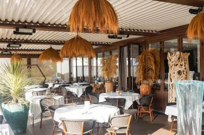 Plantes vertes en pot décorant une terrasse couverte avec des tables et des chaises disposées en arrière-plan.