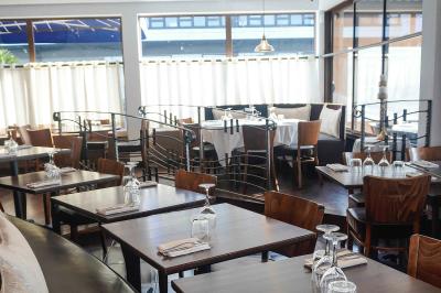 Plantes vertes en pot décorant une terrasse couverte avec des tables et des chaises disposées en arrière-plan.