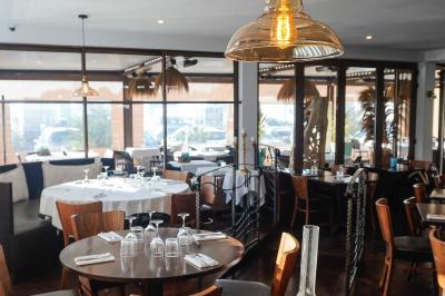 Plantes vertes en pot décorant une terrasse couverte avec des tables et des chaises disposées en arrière-plan.