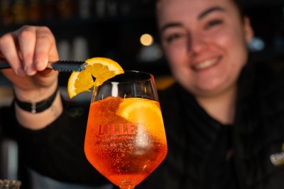 Dessert tiramisu dans une verrine, décoré d'une tranche d'orange séchée, avec une main tenant une cuillère.