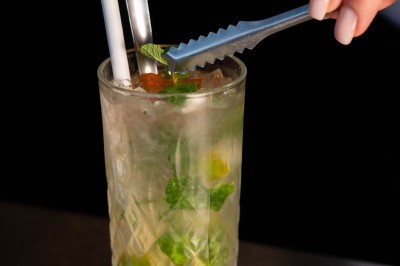 Dessert tiramisu dans une verrine, décoré d'une tranche d'orange séchée, avec une main tenant une cuillère.