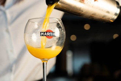 Dessert tiramisu dans une verrine, décoré d'une tranche d'orange séchée, avec une main tenant une cuillère.