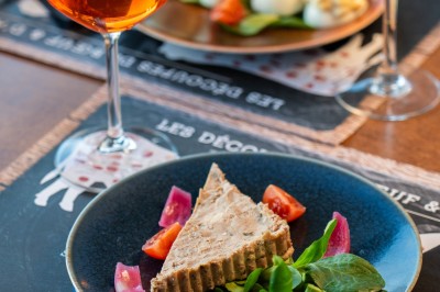 Dessert tiramisu dans une verrine, décoré d'une tranche d'orange séchée, avec une main tenant une cuillère.