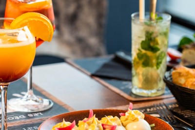 Dessert tiramisu dans une verrine, décoré d'une tranche d'orange séchée, avec une main tenant une cuillère.