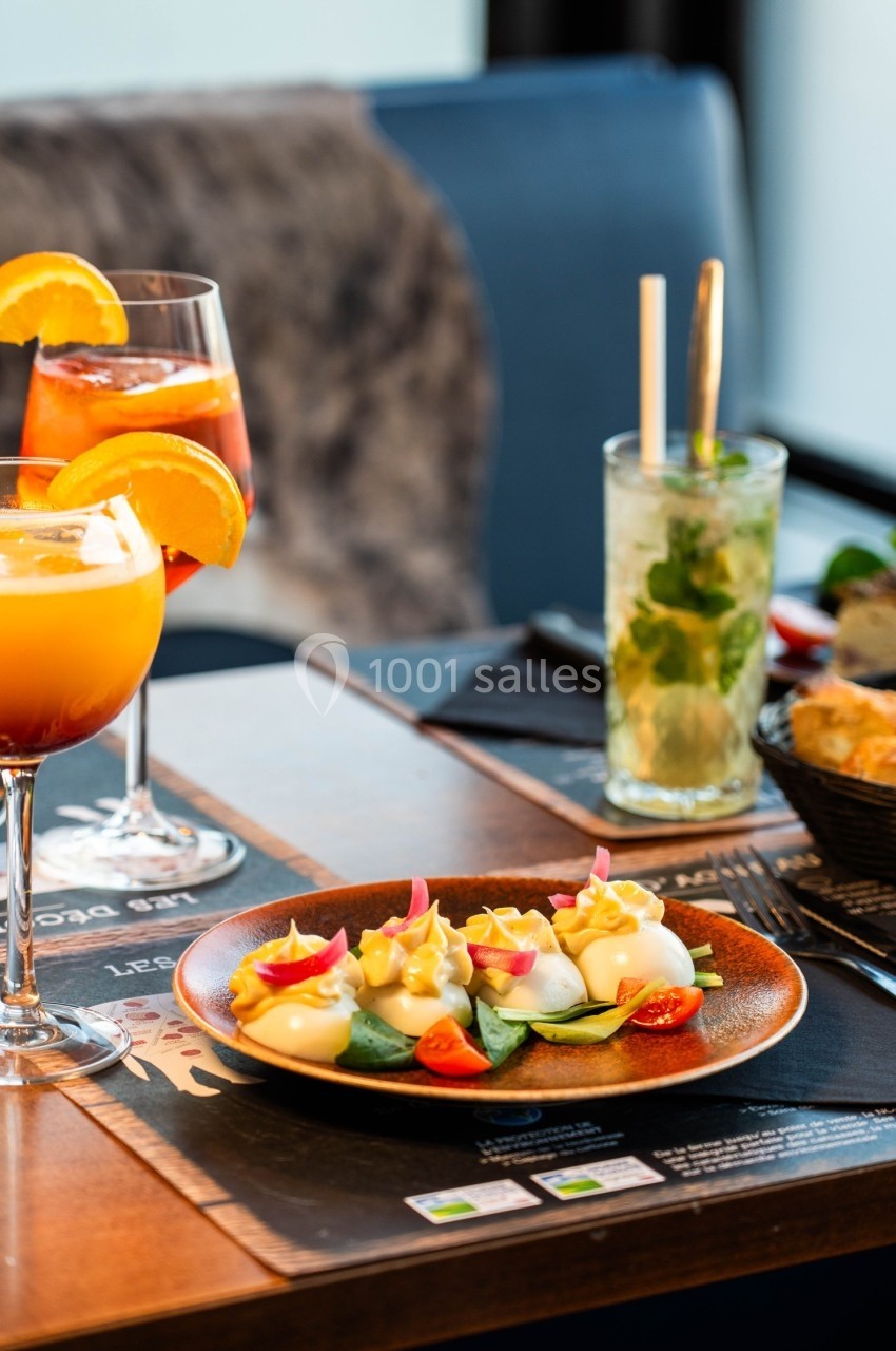 Assiette de légumes garnis de sauce à côté de cocktails colorés sur une table de restaurant.