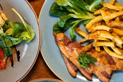 Dessert tiramisu dans une verrine, décoré d'une tranche d'orange séchée, avec une main tenant une cuillère.