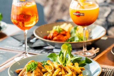 Dessert tiramisu dans une verrine, décoré d'une tranche d'orange séchée, avec une main tenant une cuillère.