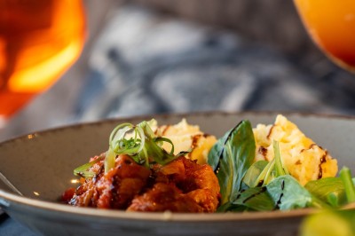 Dessert tiramisu dans une verrine, décoré d'une tranche d'orange séchée, avec une main tenant une cuillère.